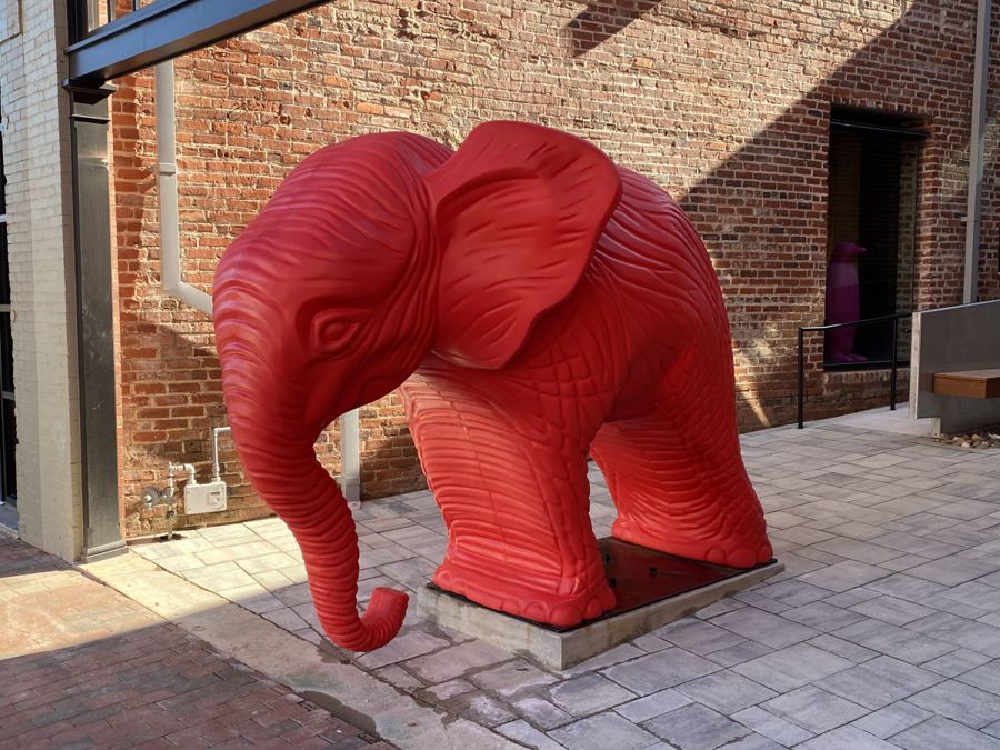The red elephant sculpture in the sunlit brick courtyard created where a collapsed drugstore once stood