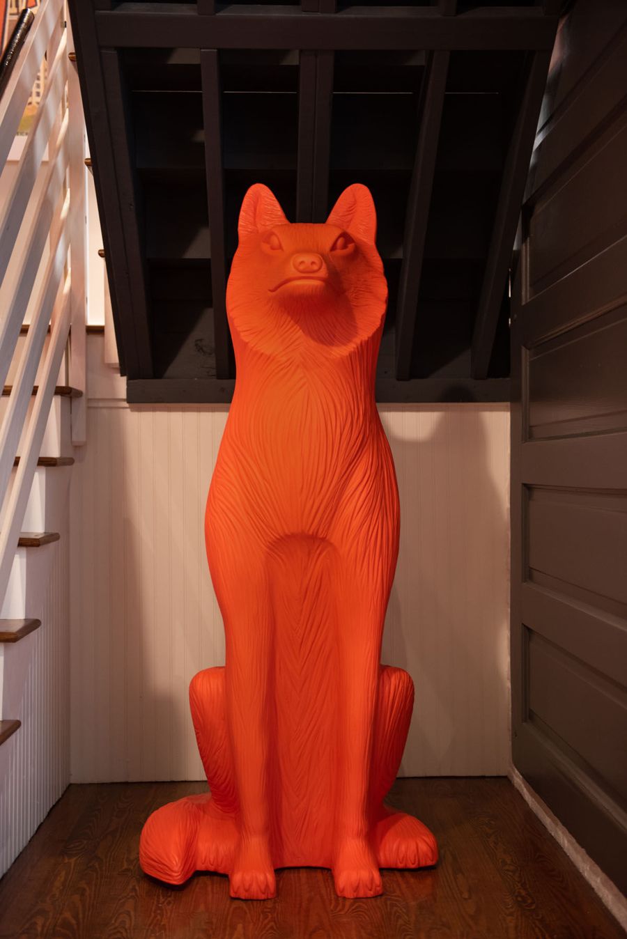 Life-size orange fox sculpture standing beneath the open staircase