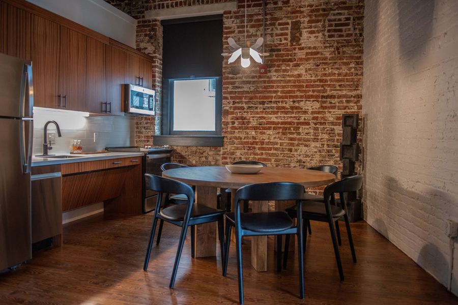 Full kitchen and round dining table set against exposed brick
