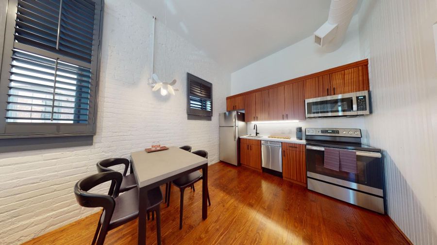 Full kitchen with wood cabinetry, stainless appliances and a dining table for four