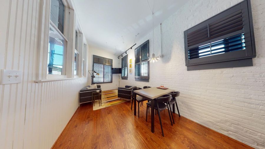 Open living and dining area with tall windows, plantation shutters and wood floors