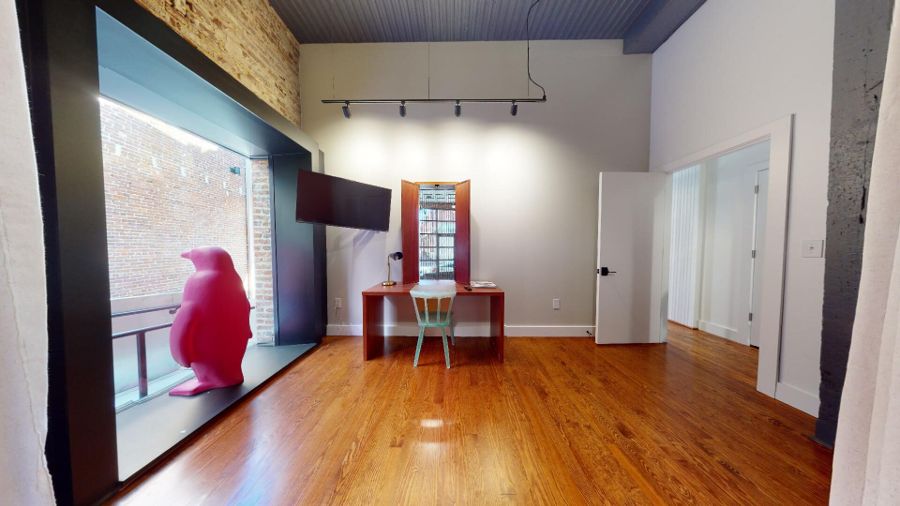 Writing desk beneath track lighting beside the penguin sculpture window