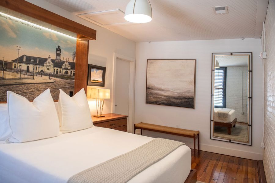 Bedroom with the postcard mural headboard, a landscape painting and a wood bench