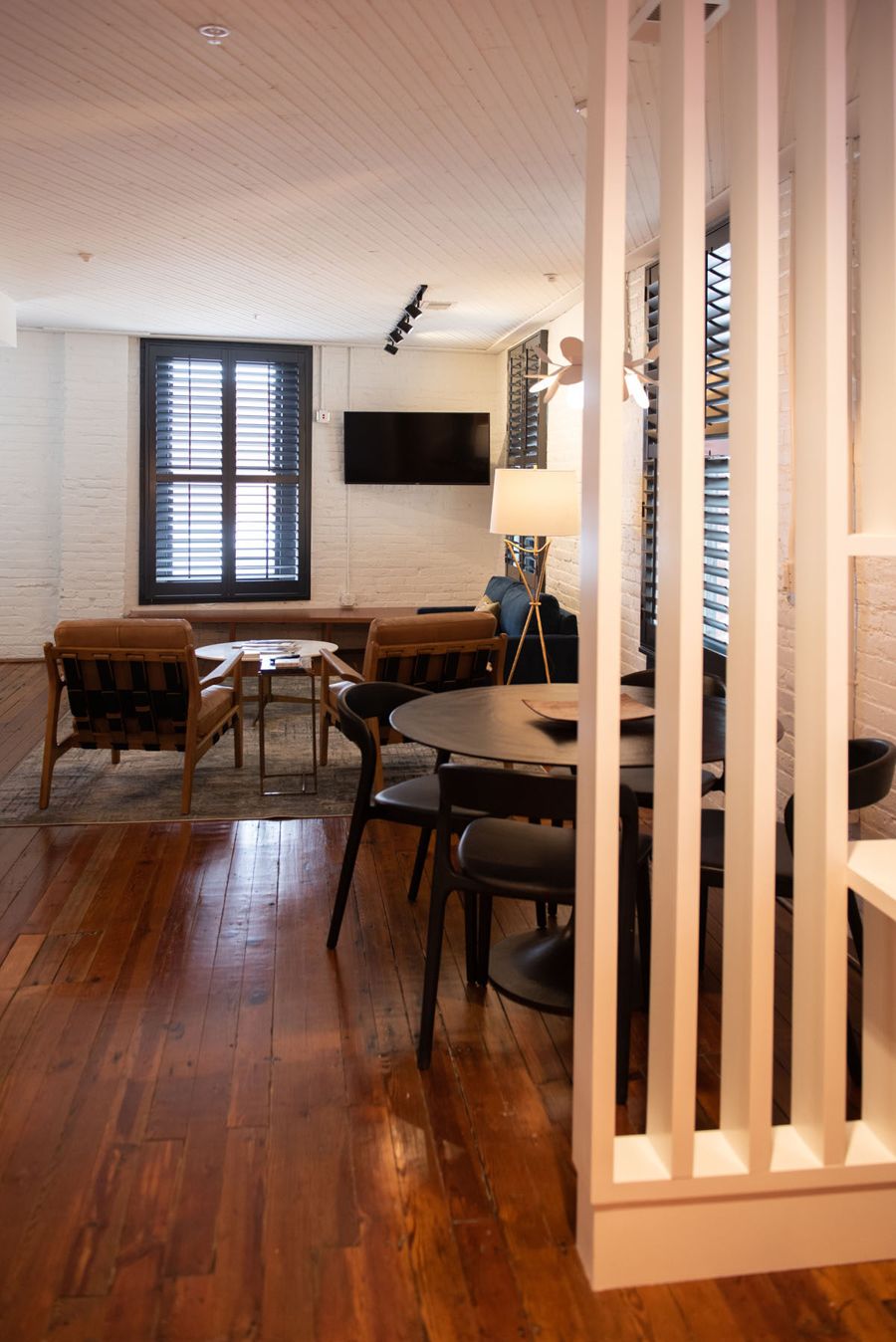 Dining table and living area seen past a white slatted room divider