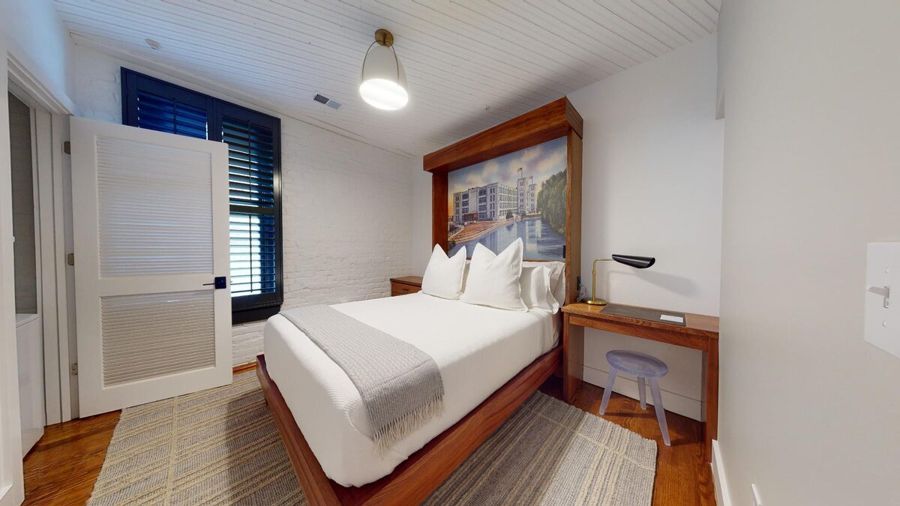 Second bedroom with a sapele headboard framing a vintage postcard of Danville mill buildings along the river