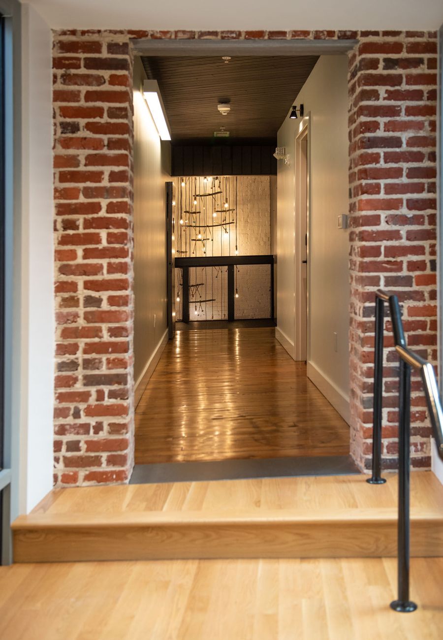 An opening cut through an original brick wall, with steps leading from one historic building into the next
