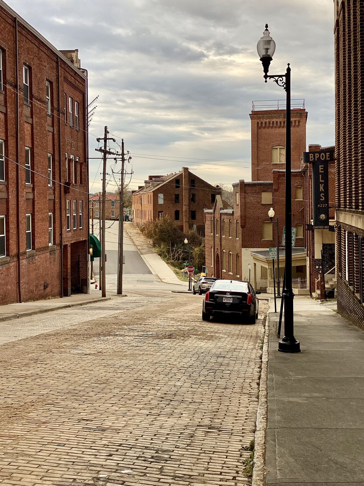 A brick-paved street lined with historic brick tobacco warehouses and an old lamppost in Danville's River District